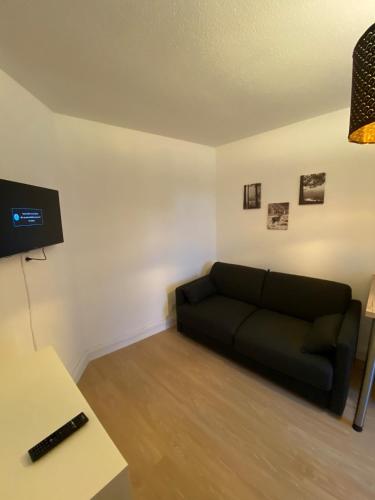 un salon avec un canapé noir et une télévision dans l'établissement New Studio Downtown Salins, à Clermont-Ferrand