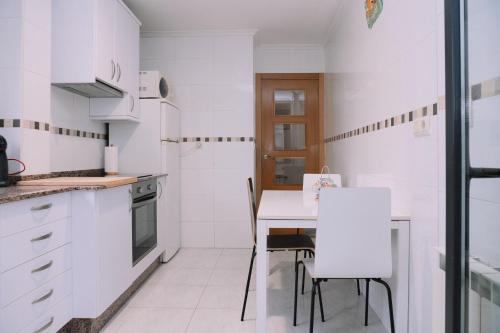 a white kitchen with a table and chairs at Vistas al mar en el centro by CABANA Rentals in Moaña