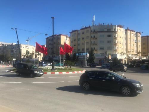 a black car driving down a street with red flags at Appartement Familial en Face le Stade Ibn Batouta Tanger in Tangier