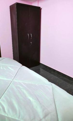 a bedroom with a white bed and a brown cabinet at Samuels Comfort Homes in Bengaluru