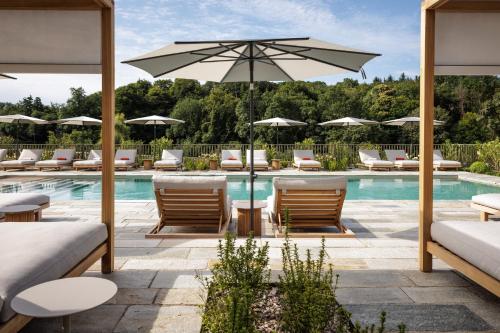 a pool with chairs and umbrellas next to a pool at Domaine de Locguénolé & Spa - Relais & Chateaux in Kervignac