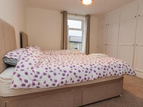 a bedroom with a bed with a purple comforter and a window at 163 Manchester Road in Accrington