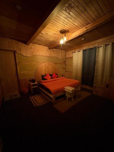a bedroom with a bed with red pillows on it at Kath Kuni Cafe & Stay Shangarh in Shangarh