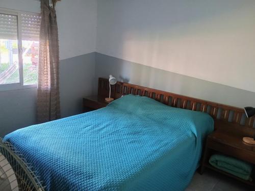 a bedroom with a bed with a blue comforter and a window at PRAZER, Casa de Vacaciones en Barra del Chuy, Sol, Mar, Comodidad y compras a 400 mts del mar, se reserva con seña! in Barra del Chuy