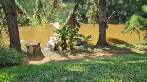 a park with a pond and trees and a bench at Casa de Vidro na Mata, com Lago, cachoeira, caiaque, Stand up, escorregador no lago in Itatiba