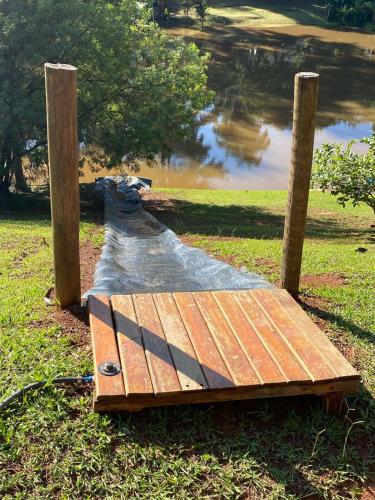 a wooden boardwalk next to a body of water at Casa de Vidro na Mata, com Lago, cachoeira, caiaque, Stand up, escorregador no lago in Itatiba