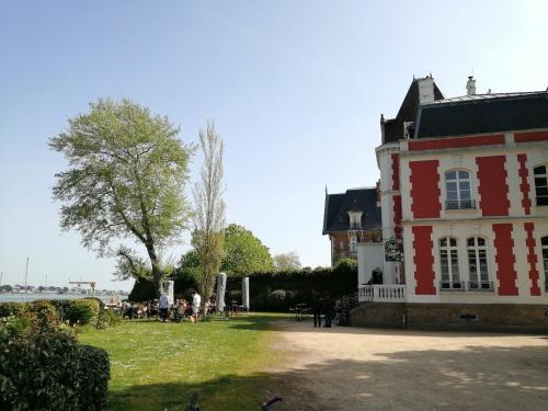 Un bâtiment rouge et blanc avec des gens assis sur l'herbe dans l'établissement Charmant studio indépendant à 2 pas de la plage, à Larmor-Plage