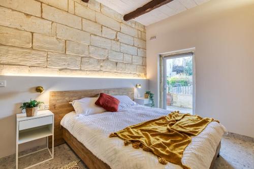 a bed in a room with a stone wall at Beautifully Renovated 3BR Sliema Townhouse in Sliema