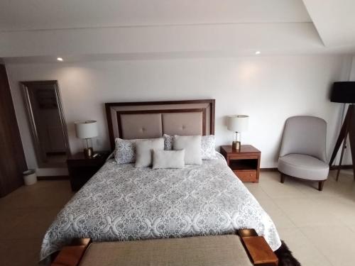 a bedroom with a bed with pillows and a chair at Nima Bay, Marina Vallarta in Puerto Vallarta