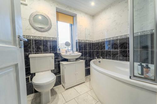 a bathroom with a tub and a toilet and a sink at Kilmallie House in Caol