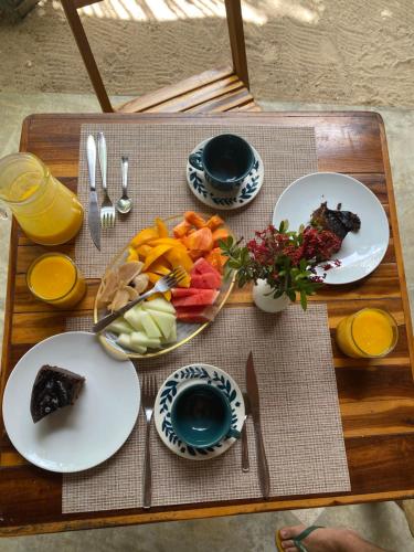 a wooden table with plates of food on it at Pousada Águas de Tamandaré in Tamandaré