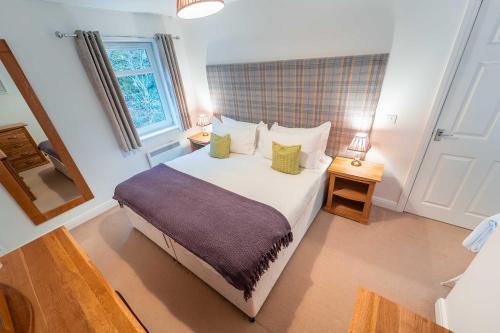 1 dormitorio con 1 cama grande, 2 mesas y ventana en Druimarbin Falls, en Fort William