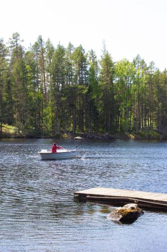 a man in a boat on a lake with a dock at Haven Islands incredible treehouse on private island in Torrflonäs