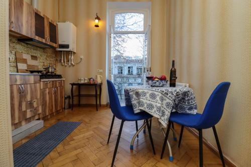 a kitchen with a table with blue chairs and a window at Leon Rooms in Tbilisi City