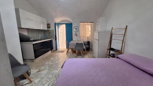 a bedroom with a purple bed and a kitchen at Appartamento nel centro storico di Peschici in Peschici