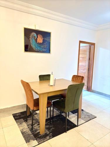 a dining room table with chairs and a painting on the wall at Hope guests home in Douala