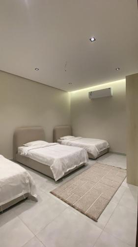 two beds in a room with white walls at شقه مفروشة ببطحاء قريش in An Nikāshah