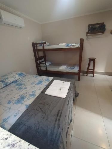 a bedroom with a bed and a shelf with towels at Flat Familiar em Capitolio Charlene Paiva in Capitólio