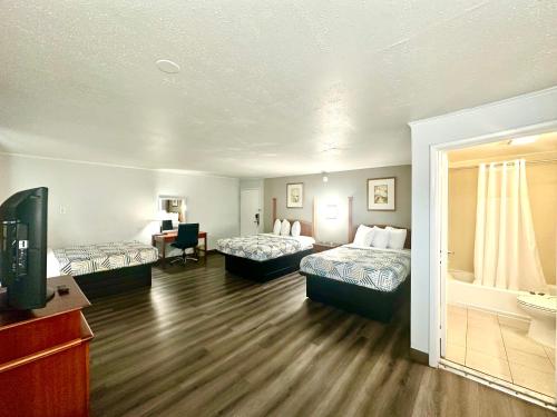 a hotel room with two beds and a television at Red Carpet Inn - Stamford in Stamford