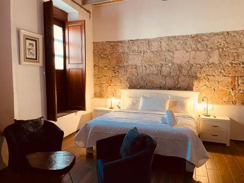 a bedroom with a white bed and two chairs at Casa De Los Remedios Morelia in Morelia