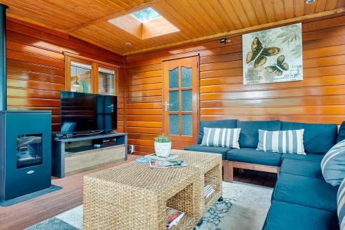 a living room with a blue couch and a tv at Luxe chalet met jacuzzi en sauna in Erm