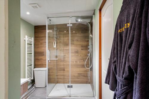 a shower with a glass door in a bathroom at Luxe chalet met jacuzzi en sauna in Erm