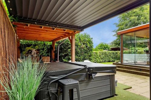 a barbecue in a backyard with a wooden pergola at Luxe chalet met jacuzzi en sauna in Erm