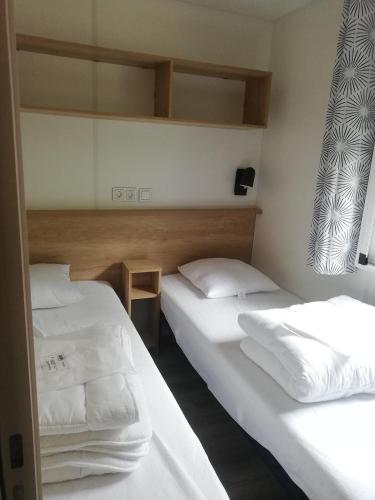 Cette chambre comprend 2 lits avec des draps et des oreillers blancs. dans l'établissement Mobil-Home 2 chambres, à Ascou