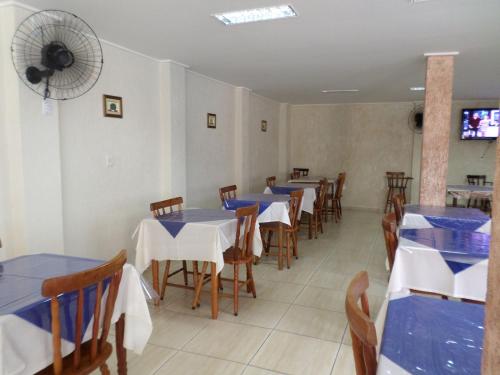 a dining room with tables and chairs and a fan at Pousada Iracema in Guarujá