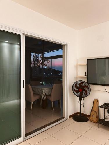 a room with a sliding glass door with a table and a television at Cobertura com Banheira e Cama King in Cabo Frio