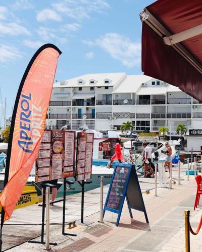 a sign with a surfboard in front of a pool at Superbe studio avec Piscine, au coeur de la Marina! Village Soleil ! Proche Aéroport & Ferry in Le Gosier