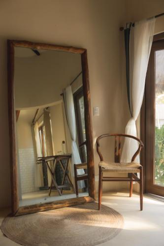 a mirror in a room with a chair in front of a room at Alquimia Hotel Boutique in Tulum