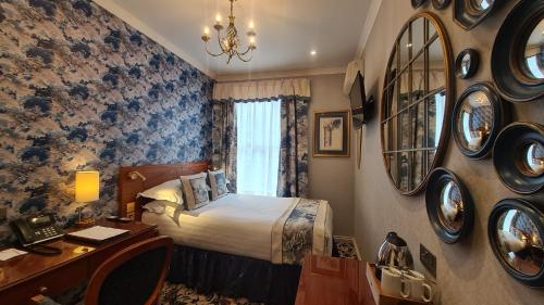 a hotel room with a bed and a desk and mirror at London Lodge Hotel in London