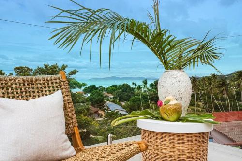 a rattan chair with a plant in a vase at Villa Umi 4 Br Private Pool & Sea View in Ban Lamai