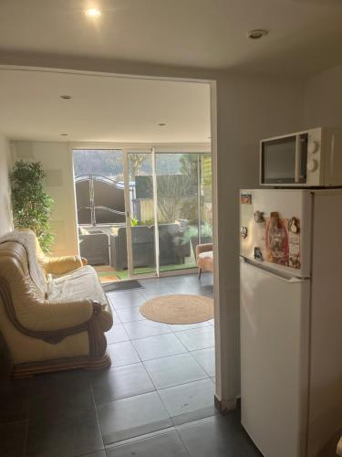 Il comprend une cuisine équipée d'un réfrigérateur, d'une chaise et d'un canapé. dans l'établissement Maison bord de Seine, à Sotteville-lès-Rouen