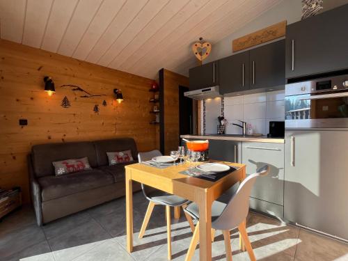 une cuisine avec une table, des chaises et un canapé dans l'établissement Cottage contemporain Cosy & Chic, à Prémanon