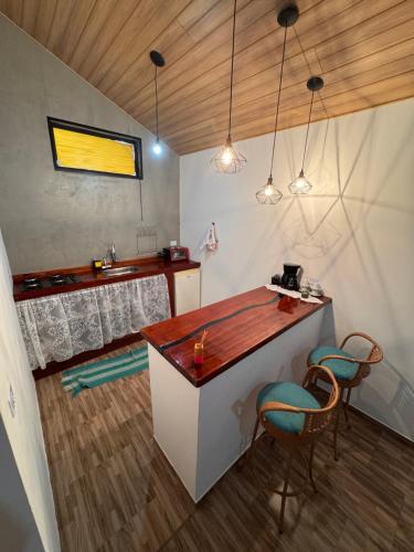 a kitchen with a counter and chairs in a room at Chalé Primavera em Gonçalves in Gonçalves