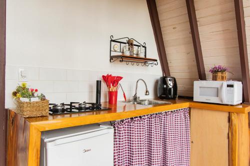 eine Küche mit Herd und Mikrowelle in der Unterkunft Chalé Charlotte l Maravilhoso para Casal in Campos do Jordão