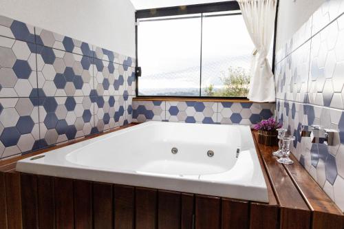 eine große Badewanne im Bad mit Fenster in der Unterkunft Chalé Charlotte l Maravilhoso para Casal in Campos do Jordão