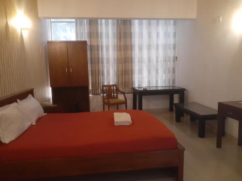 a bedroom with a bed and a desk and a chair at Sanford Hotel & Restaurant Colombo in Wattala
