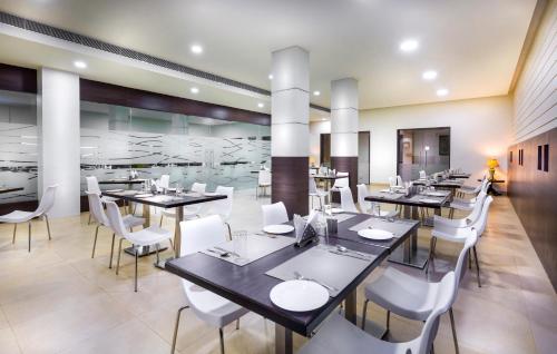 Tiruttani蒂鲁塔尼GRT丽景酒店的带桌子和白色椅子的餐厅