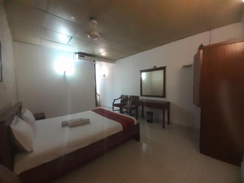a bedroom with a bed and a table and a desk at Sanford Hotel & Restaurant Colombo in Wattala