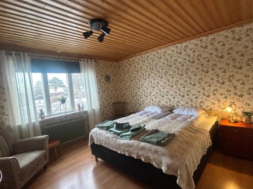 a bedroom with a bed and a chair and a window at Fyra rum och kök i Mellanfjärden in Mellanfjärden