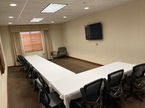 a conference room with white tables and chairs and a tv at Holiday Inn Express Hotel & Suites Howell by IHG in Howell