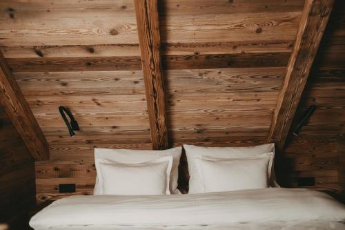 a bed with two pillows in a room with wooden walls at Hotel Rosenhof Murau in Murau