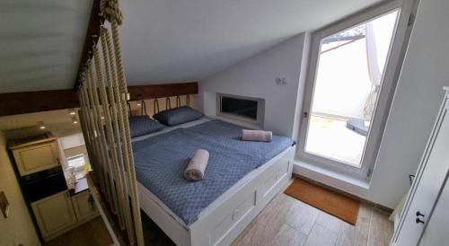 a bedroom with a bed with blue sheets and a window at Apartman Manuela in Pag