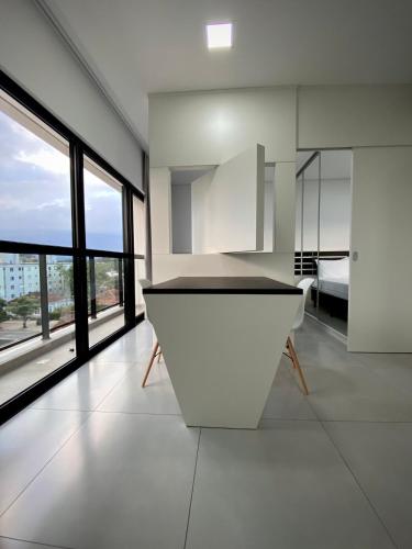 a white kitchen with a sink and large windows at MaxLoft V- Apto residencial completo in Joinville