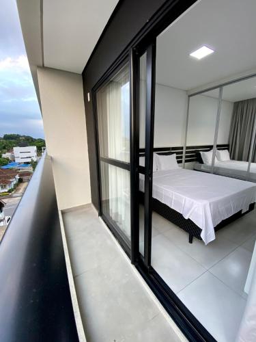 a bedroom with a bed on a balcony at MaxLoft V- Apto residencial completo in Joinville