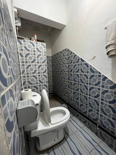 a bathroom with a toilet and blue and white tiles at L'orée du bois in Mbala