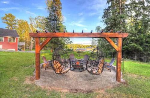 a wooden gazebo with chairs and a fire place at Beautiful Spacious & Well-Stocked Downtown Home in Rangeley